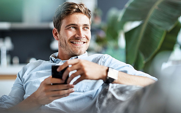 Junger Mann mit Kaffee-Tasse auf einem Sofa